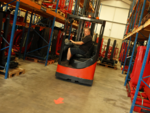 a red arrow is being displayed on a warehouse floor from a red forklift truck