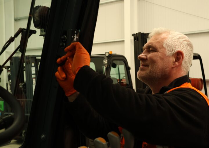 Gary Kelly installs a Safety Shield indicator onto a black forklift truck