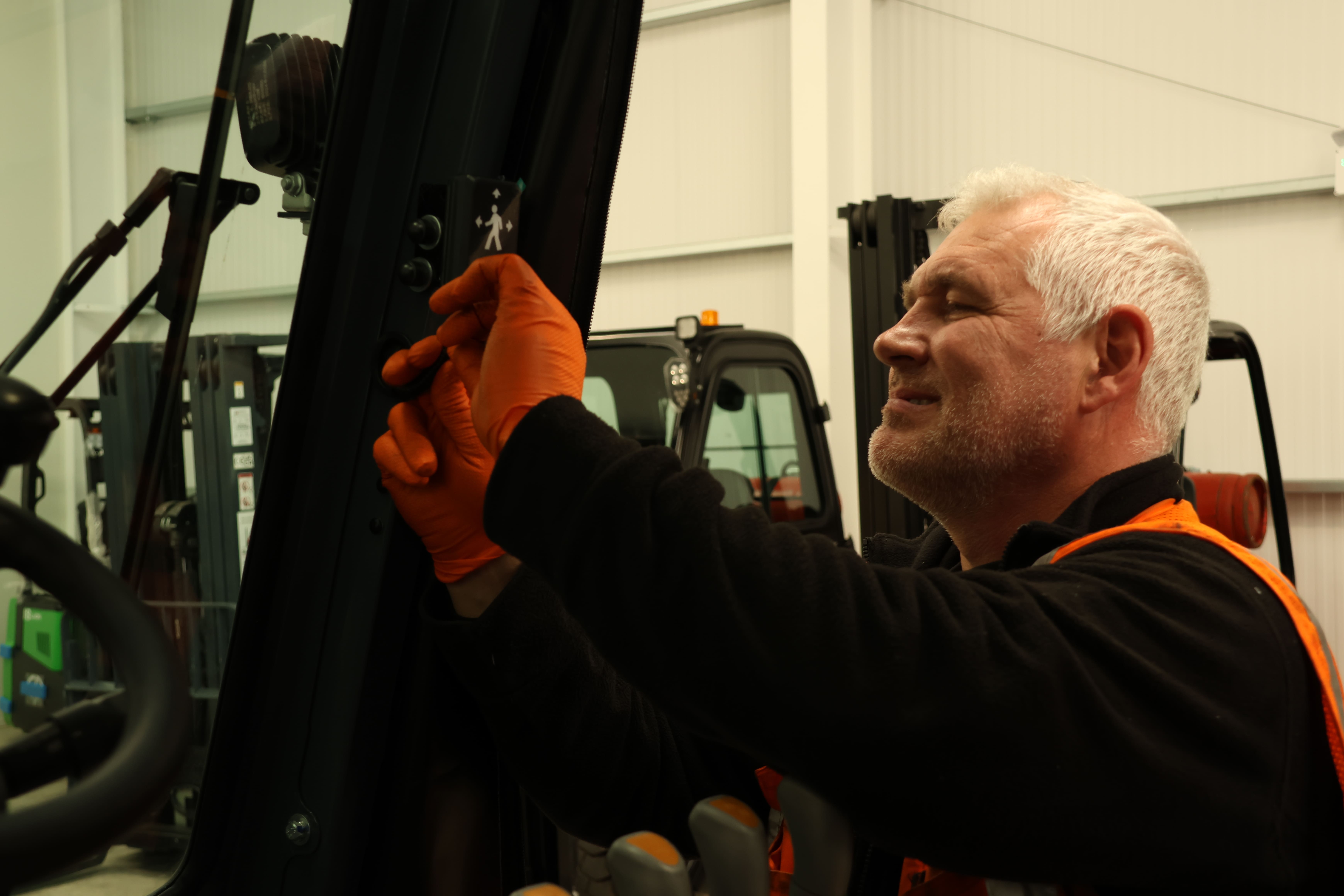 Gary Kelly installs a Safety Shield indicator onto a black forklift truck