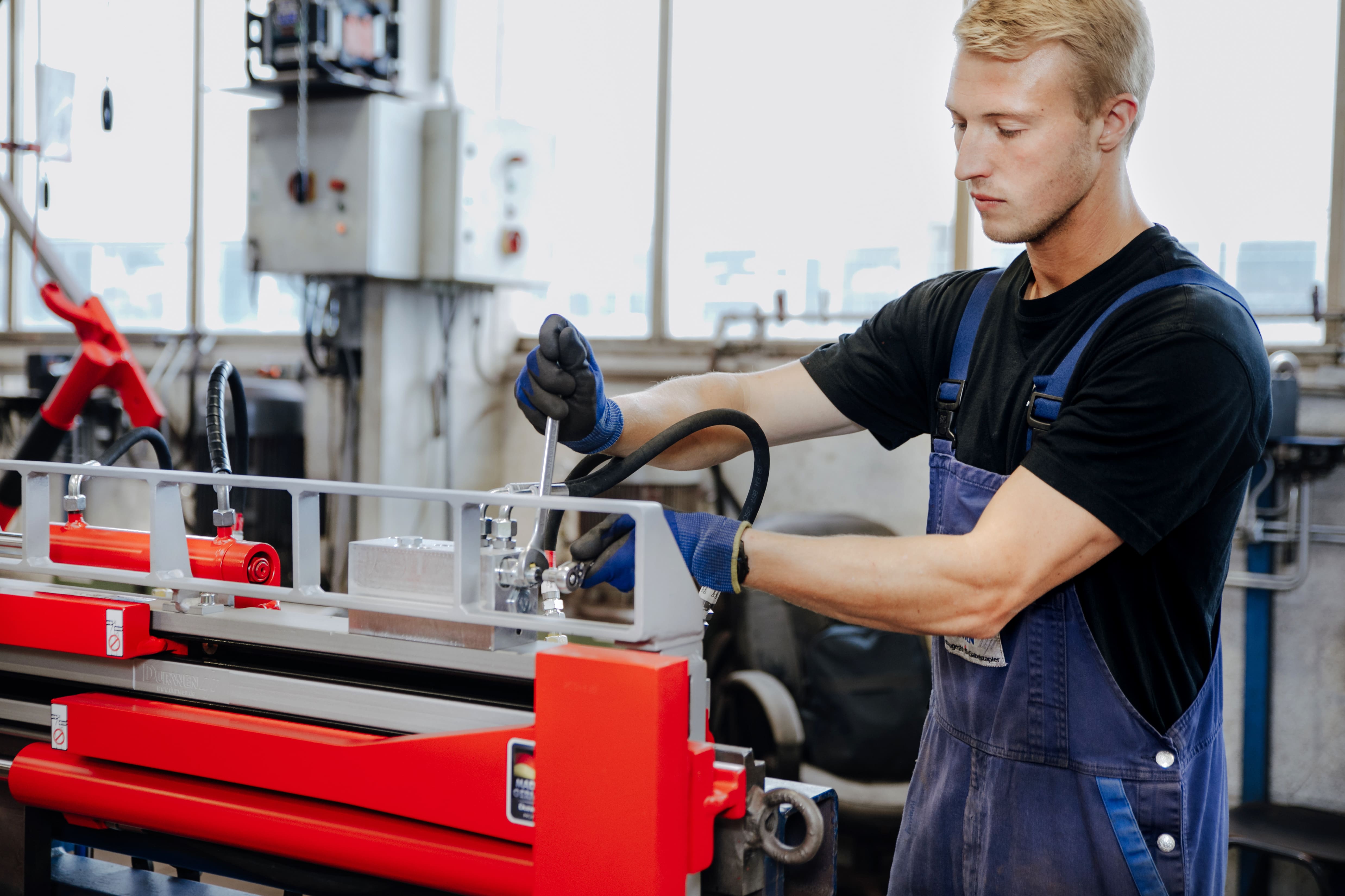 A durwen enginner is a blue uniform is working on a red attachment