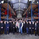 the entire abbey team wearing the black abbey jumpers are in a large warehouse surrounded by racking shelves