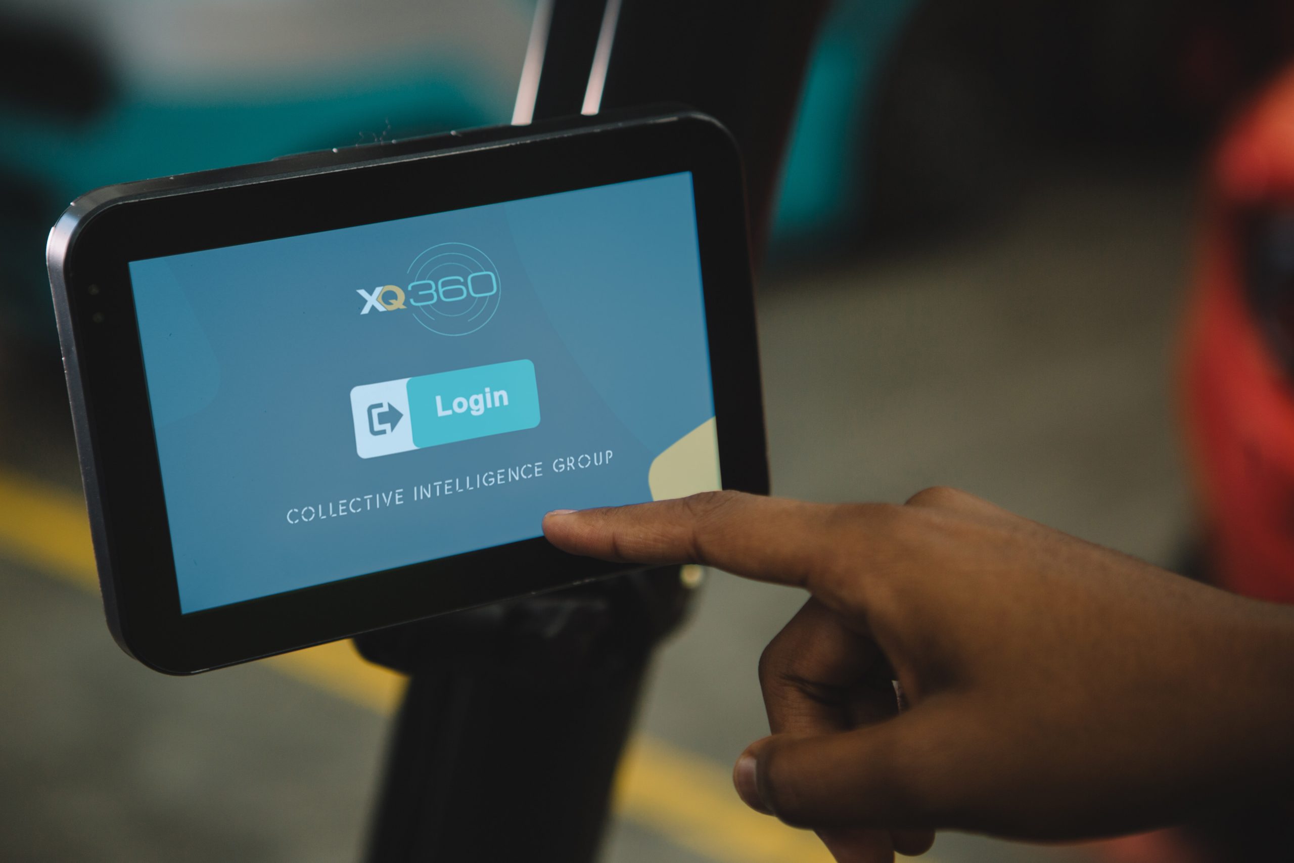 the xq360 forklift telematics system login page is visible on a touchscreen monitor, while an operator is attempting to press the screen