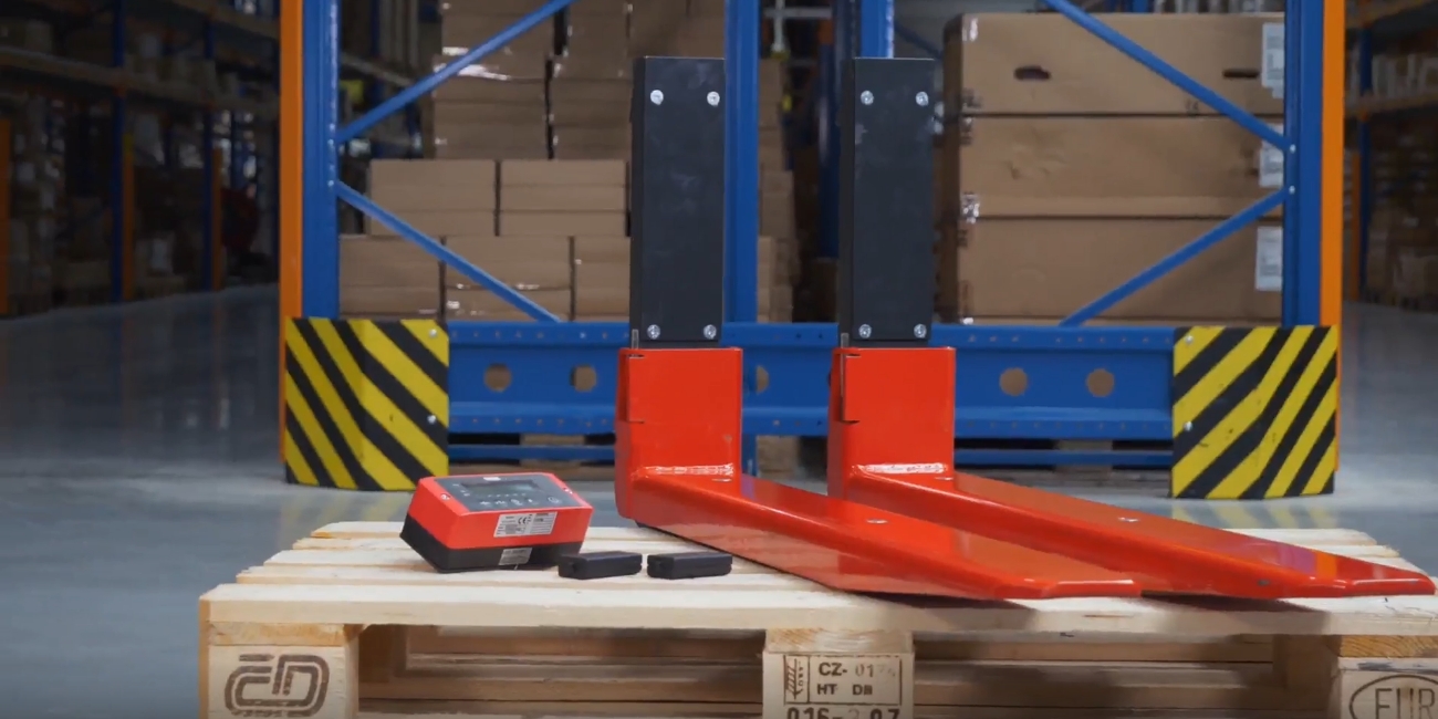 A pair of red ravas iforks are placed on wooden pallet in a dark warehouse