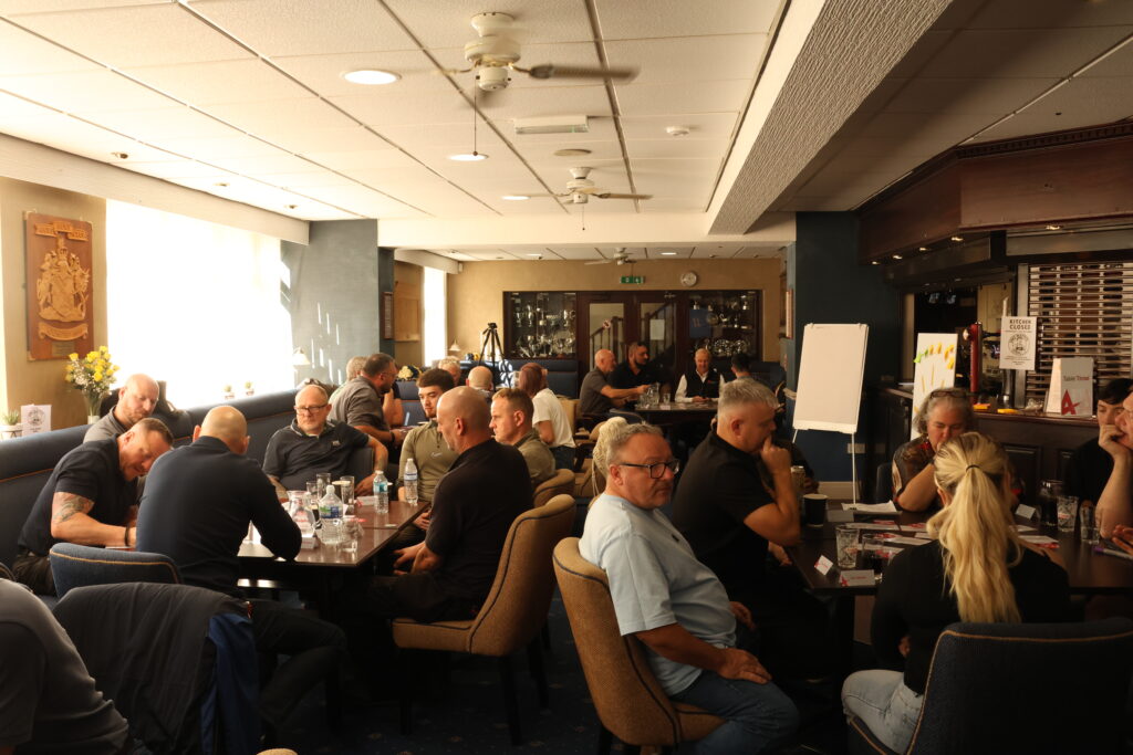the abbey staff inside a function room sitting around six square tables at the abbey day
