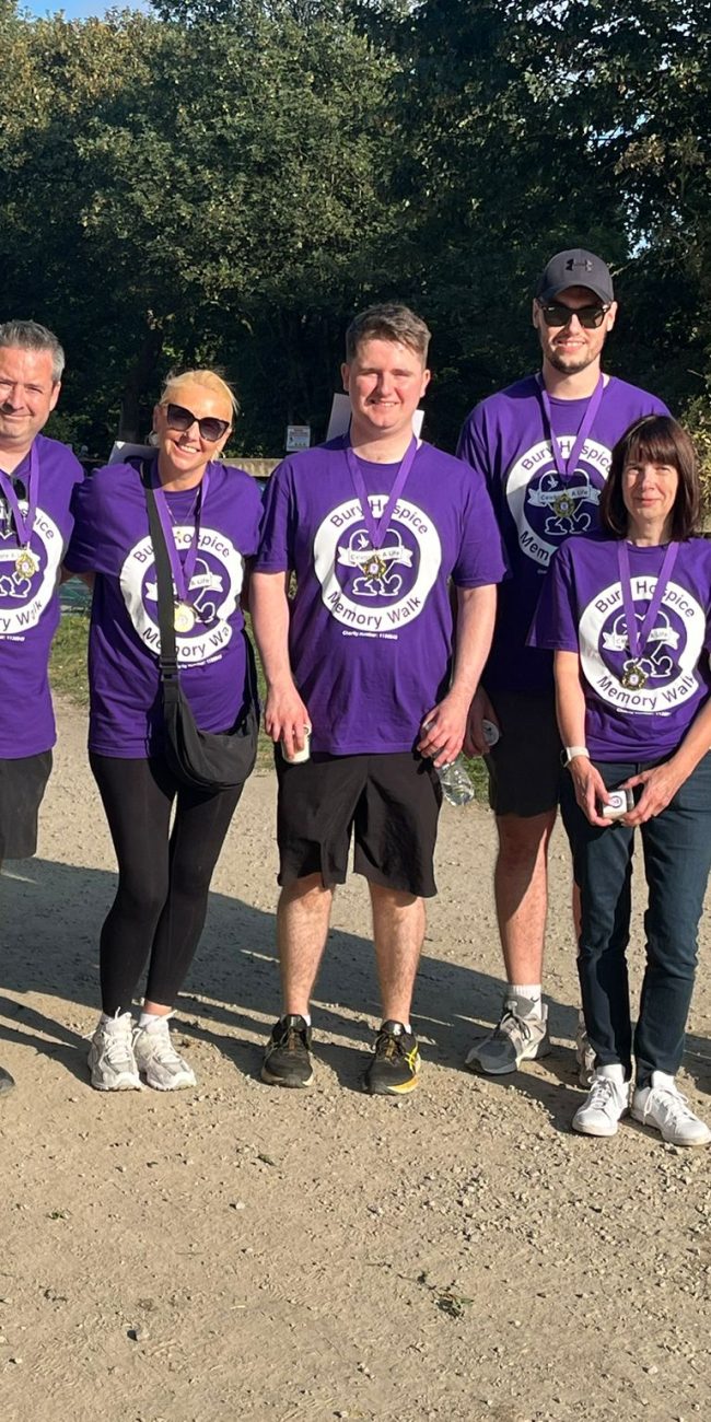 abbey staff members are wearing purple coloured memory walk 2025 t shirts with gold medals round their necks