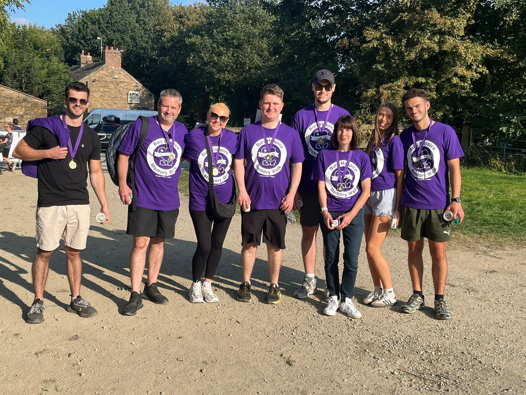 abbey staff members are wearing purple coloured memory walk 2025 t shirts with gold medals round their necks