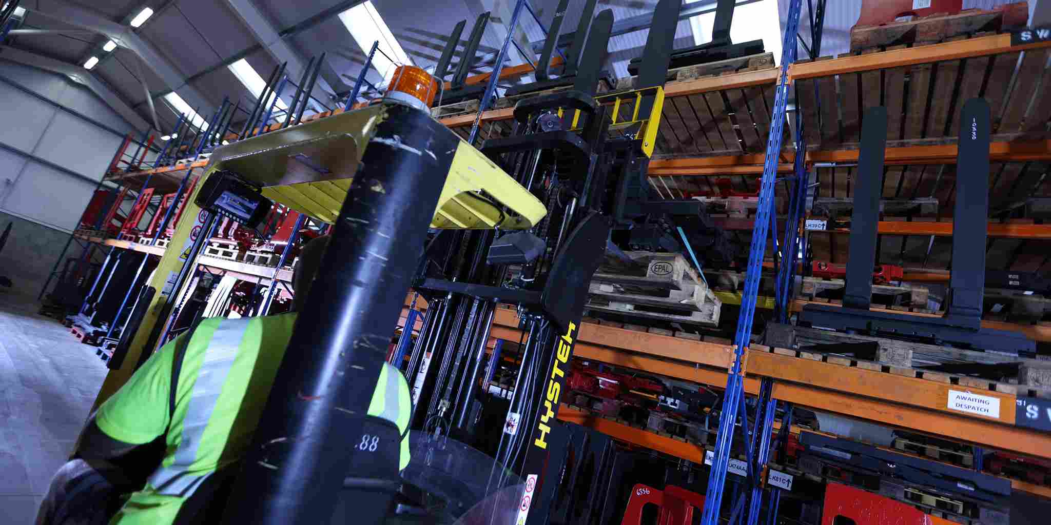 A wide shot of a yellow hyster yal forklift truck is retrieving a pallet in double deep storage from high racking