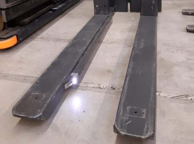 a close up of the kooi® reachforks on a cream warehouse floor