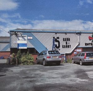 A large rctangle building with blue and grey cladded roof with a cash and carry sign on the front