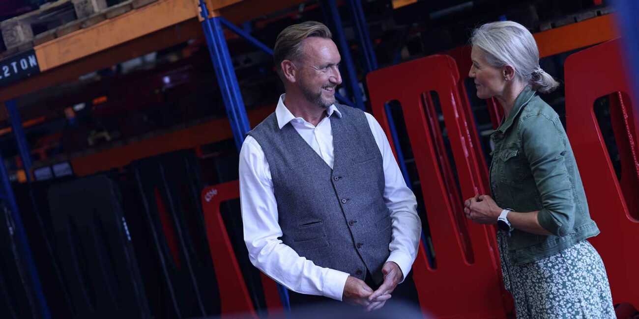Paul Saunders and Julie Graham are having a happy conversation in front of some pallet racking