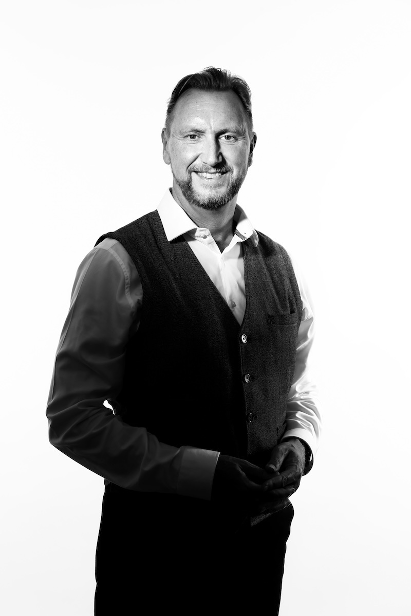 Paul Saunders, managing director of abbey, is standing wearing a white shirt and black waistcoat smiling at the camera with a black and white overlay