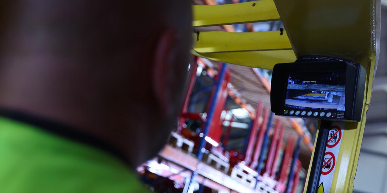 a bald operator is inside a yellow hyster yale truck looking at an rled monitor