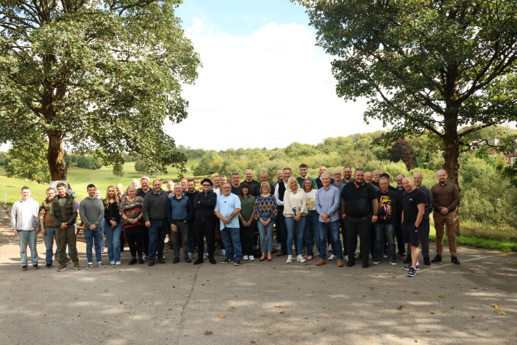the entire abbey team is standing smiling for a photo in front a well kept golf course