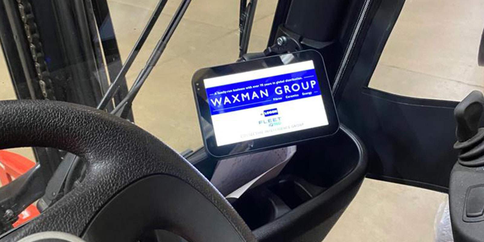 The inside of a black forklift truck holds a tablet displaying the waxman group portal homescreen